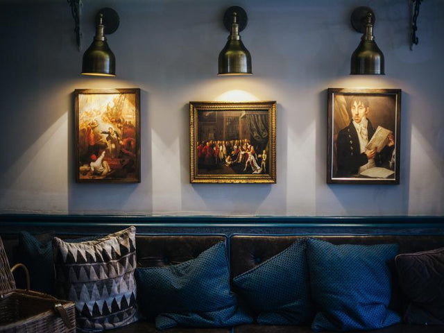 Industville wall lights shining over paintings in a hotel 