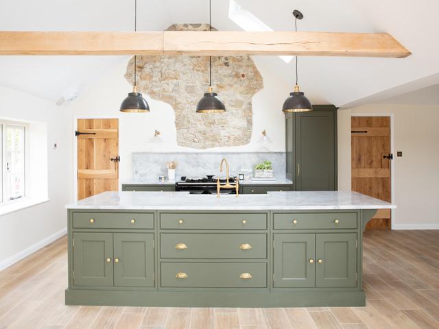Three pendants hanging over an island in a green kitchen
