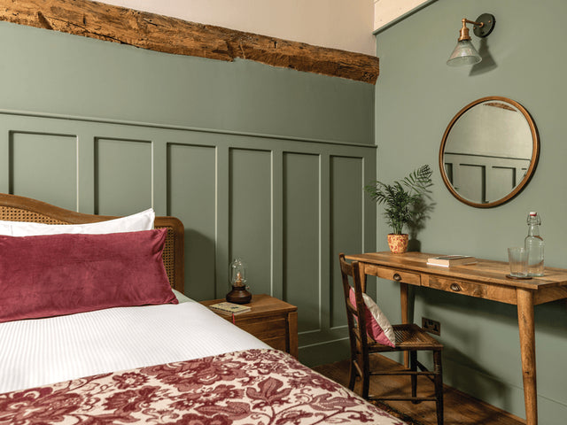 A bedroom decorated in sage green, white and red