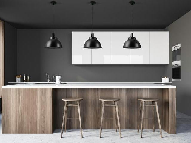 A grey kitchen with black pendant lights. 