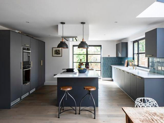 A minimalist kitchen with pewter lights and dark grey cabinets