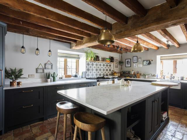A rustic kitchen with brass industrial pendant lights 