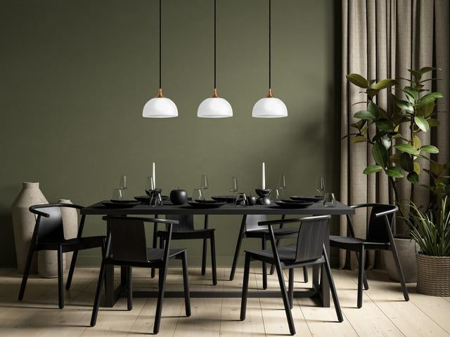 Three pendant lights hanging over a dining room in a green room