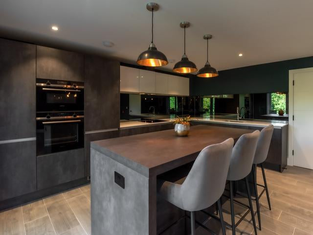 An industrial style kitchen with grey cabinets and three pewter pendant lights 