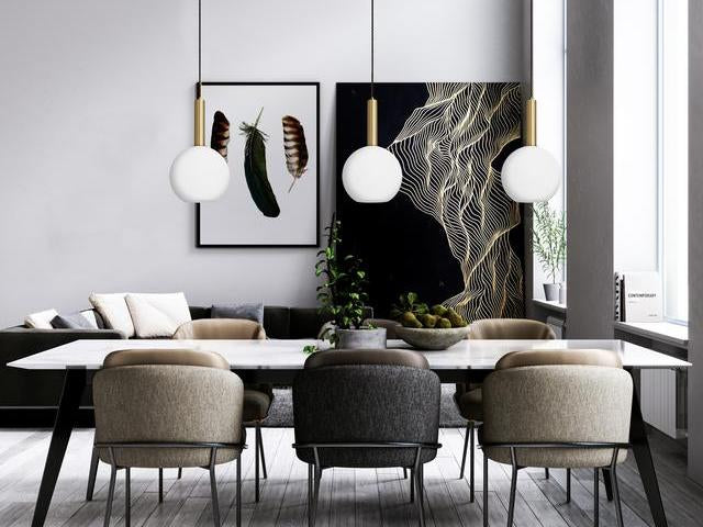 White globe pendants hanging in front of black and gold artwork. 