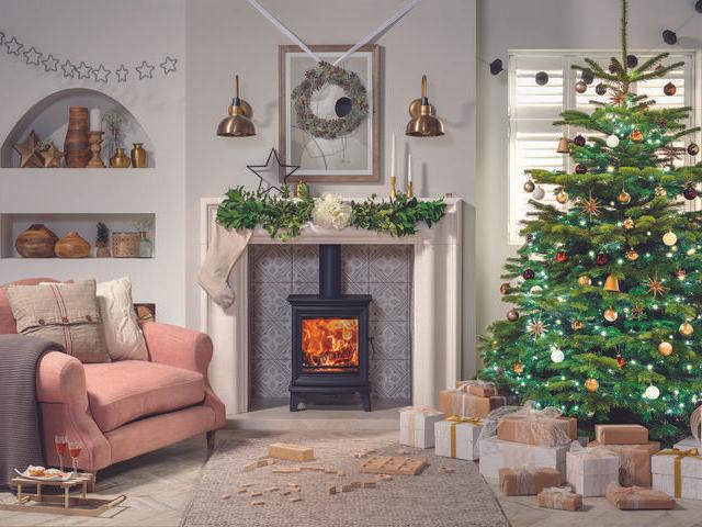 A living room with a fire decorated for Christmas