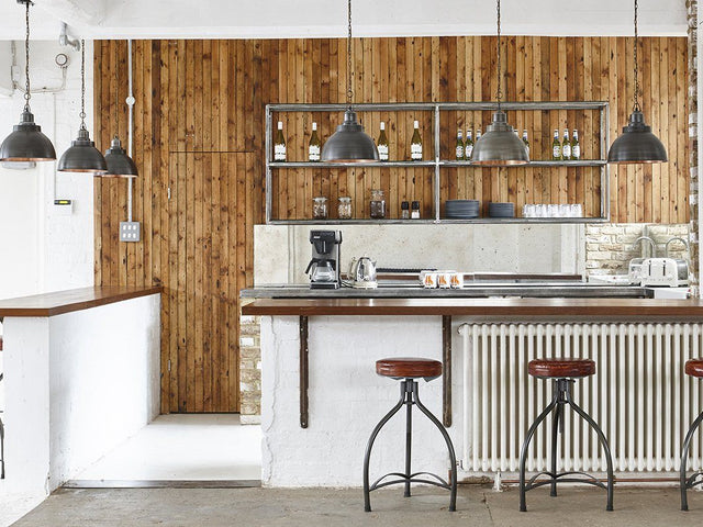 A white bar decorated with hanging industrial kitchen lights by Industville