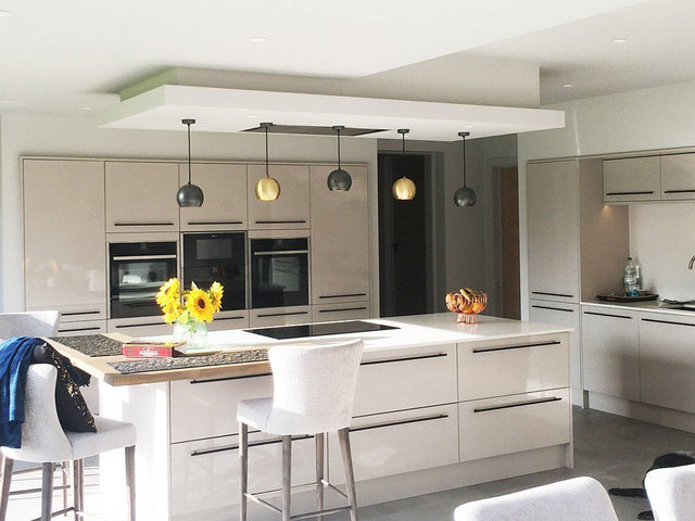 Open plan neutral kitchen interior with industrial lighting above kitchen island