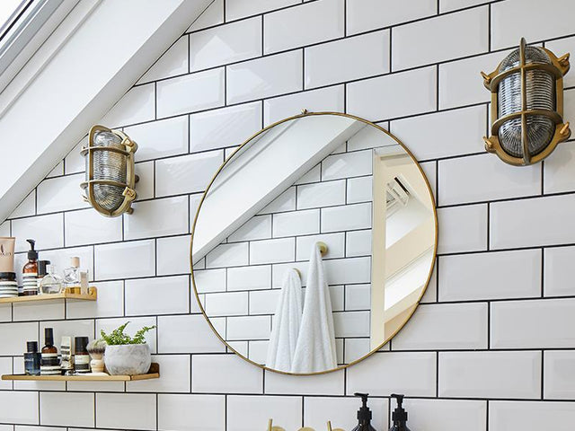 wall of a small bathroom with a mirror and industrial lighting fixtures