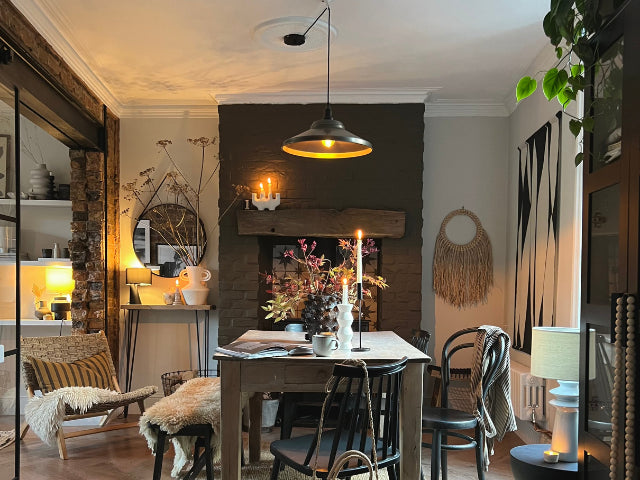 A pendant light shining over a dining room table in a rustic, Scandi-inspired space. 